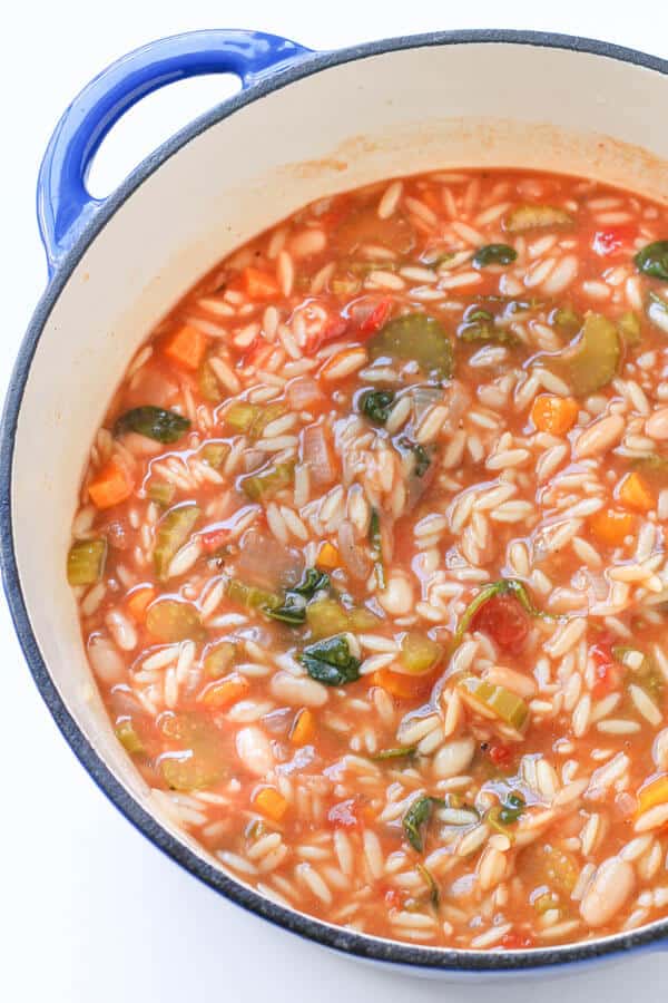 italian vegetable orzo soup in a blue rimmed dutch oven