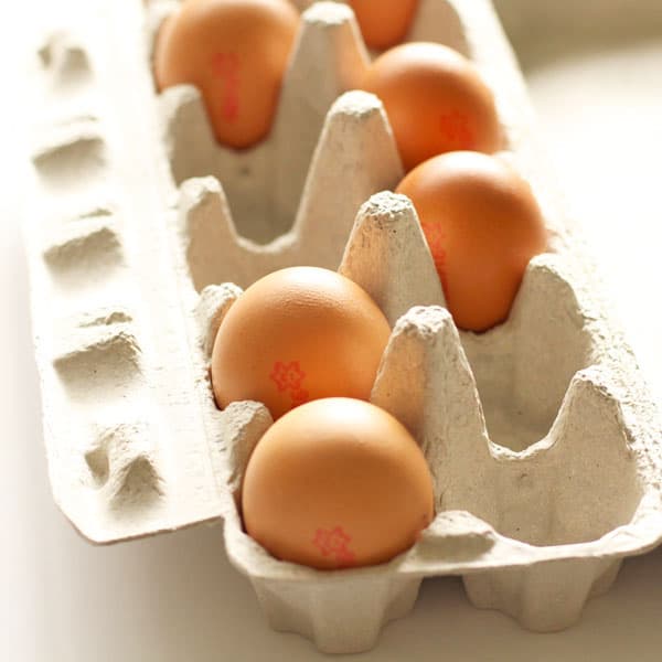 an open carton of eggs sitting on a while tabletop