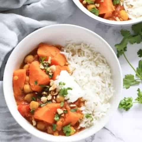 sweet potato, lentil and chickpea curry in a white bowl topped with coriander and crushed peanuts