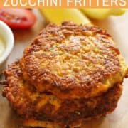 carrot and zucchini fritters stacked on a wooden board.