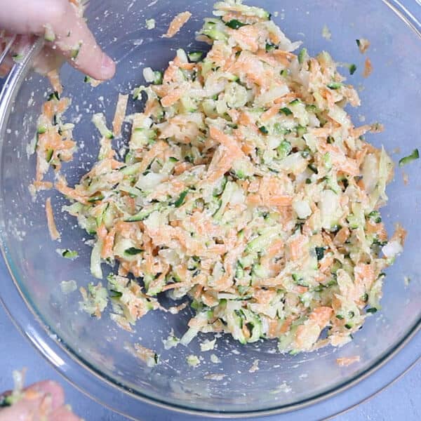 carrot and zucchini fritters mixture in a glass bowl 