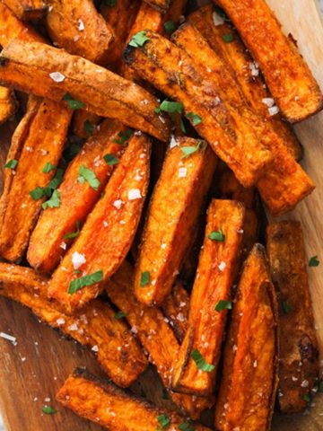 sweet potato wedges covered in salt on a wooden serving bowl.