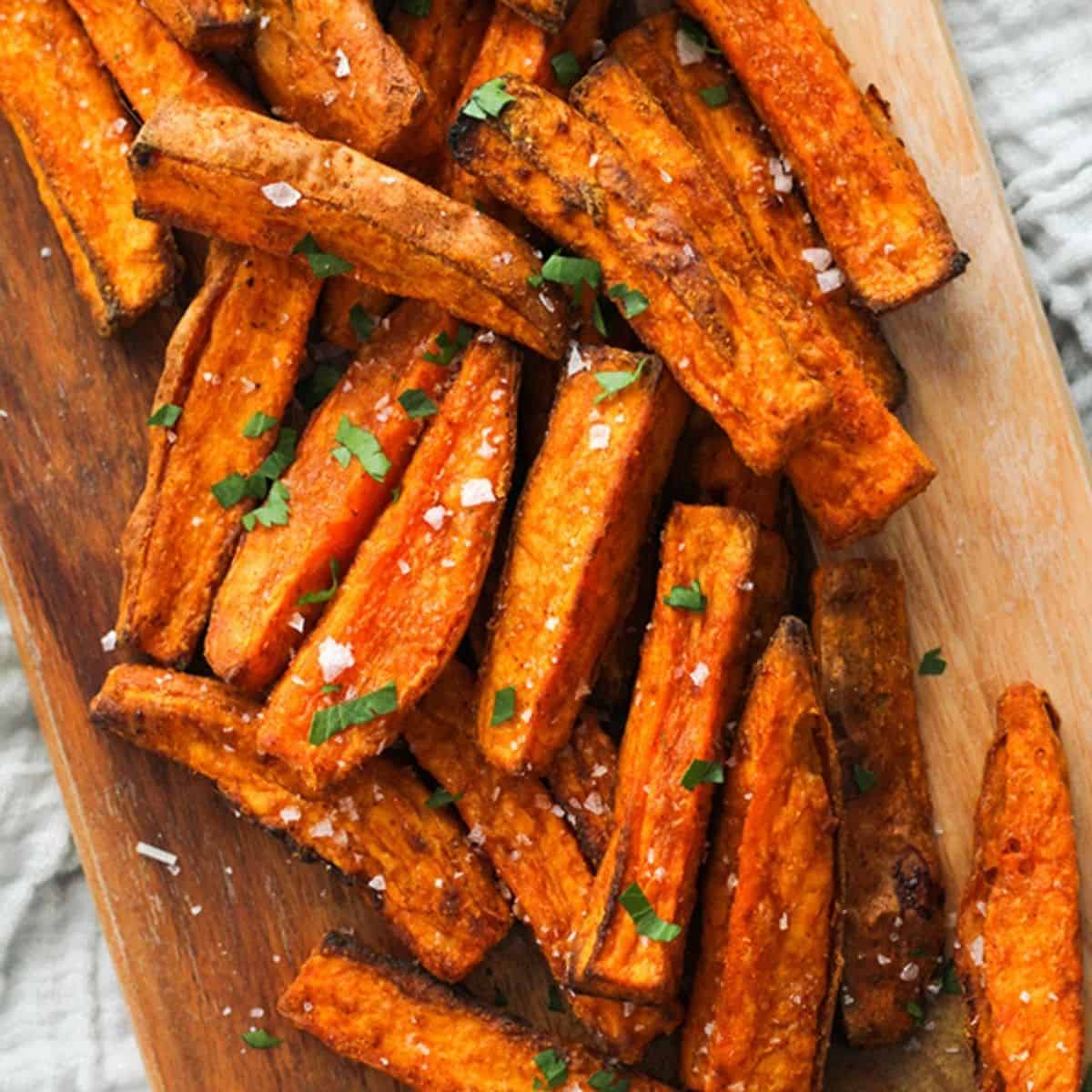 sweet potato wedges covered in salt on a wooden serving bowl.