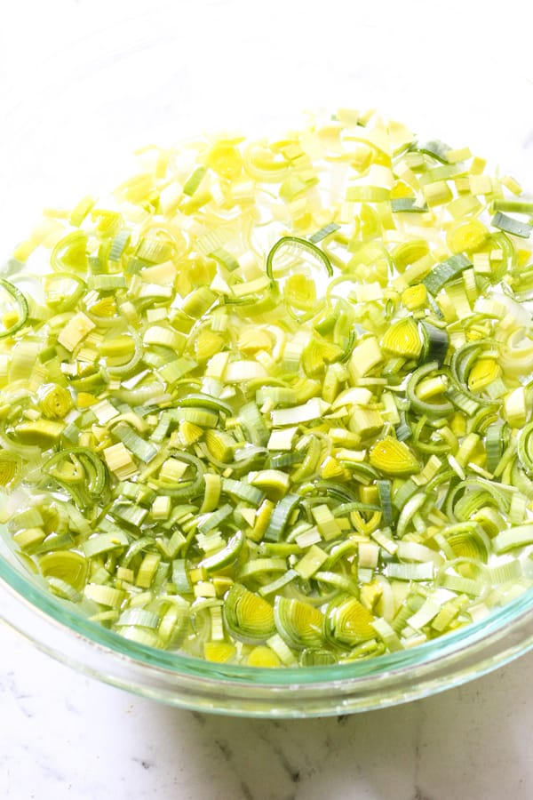 a mixing bowl filled with water and sliced leeks.