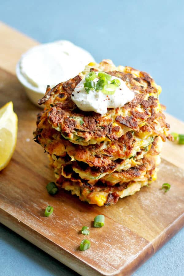 zucchini haloumi fritters stacked on a wooden serving board