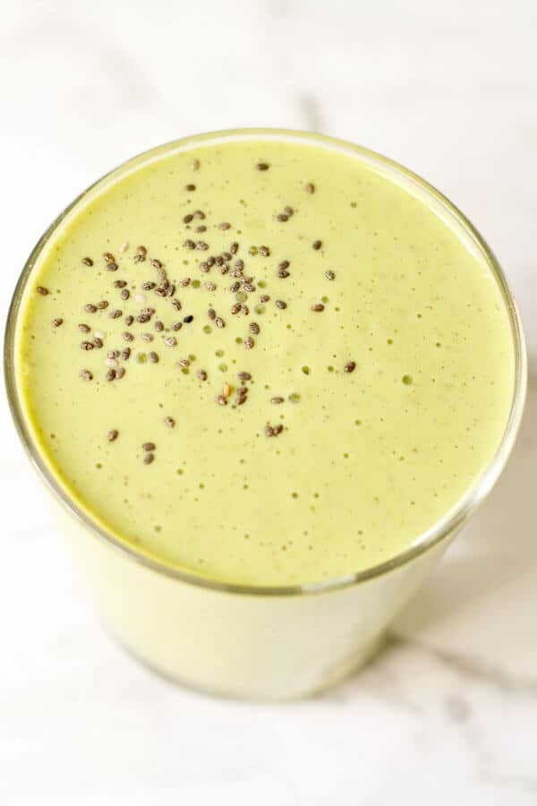 spinach mango smoothie in a glass with chia seeds sprinkled on top