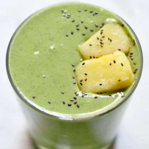 kale pineapple smoothie in a short glass topped with pineapple pieces and chia seeds