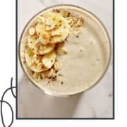 smoothie in a glass with banana slices and oats on top and text overlay "banana oatmeal smoothie".