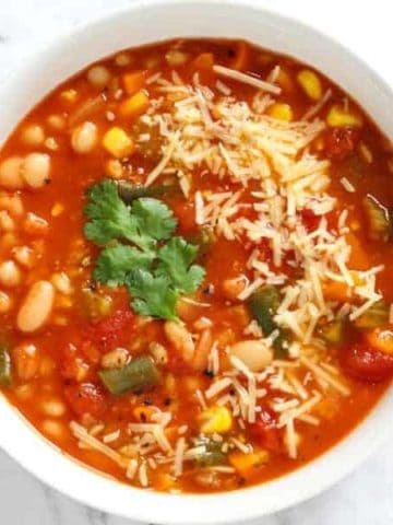 vegetable barley soup topped with parmesan cheese and coriander