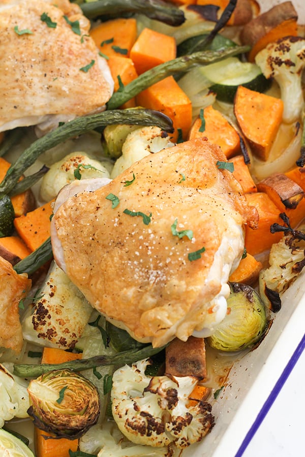 crispy baked chicken thighs on a baking tray with vegetables.