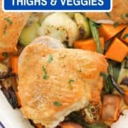 chicken thighs on a baking tray with vegetables with text overlay "crispy chicken thighs & fall vegetables".