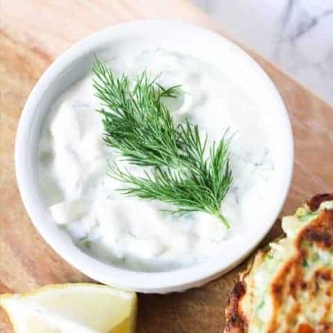 Greek Tzatziki in a white bowl with a sprig of dill on top