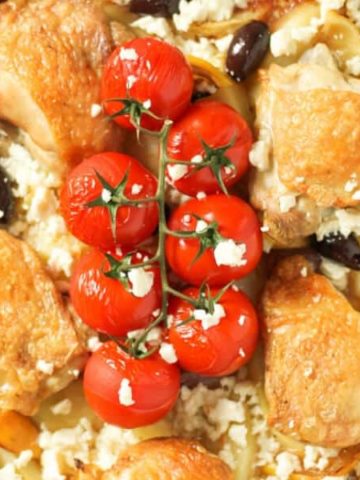 close up image of crispy skin chicken thighs and blistered cherry tomatoes