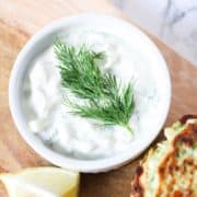tzatziki dip in a white bowl on a wooden board.
