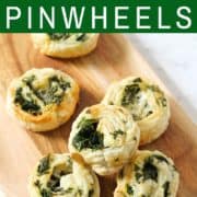 spinach and feta pinwheels on a wooden serving board.