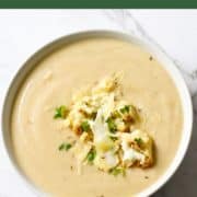 cauliflower soup in a white bowl topped with roasted cauliflower pieces.
