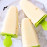 3 mango popsicles on a bed of ice cubes with text overlay "mango popsicles".