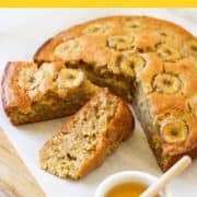 banana cake on a wooden board with a small bowl of honey with text overlay "easy banana cake".
