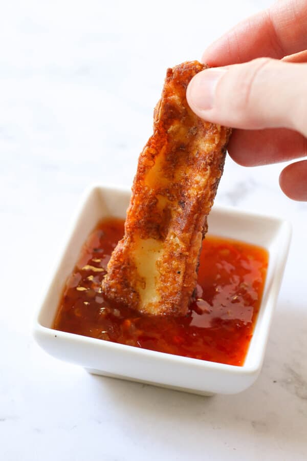 halloumi fry being dipped in sweet chilli sauce.