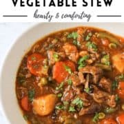 stew in a white bowl with text overlay "beef & vegetable stew".