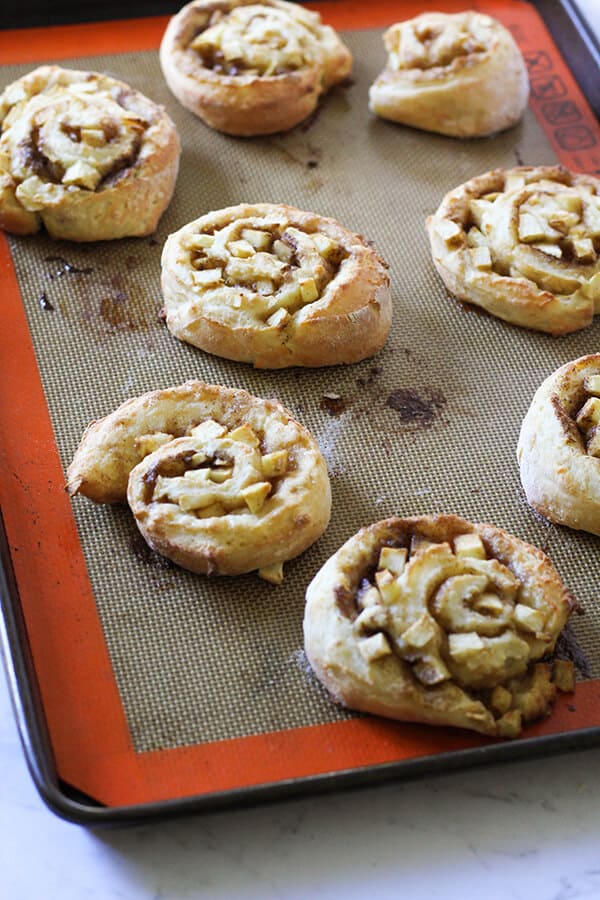 freshly baked apple cinnamon rolls on a baking tray.
