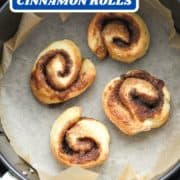 rolls in an air fryer basket with text overlay "air fryer cinnamon rolls".
