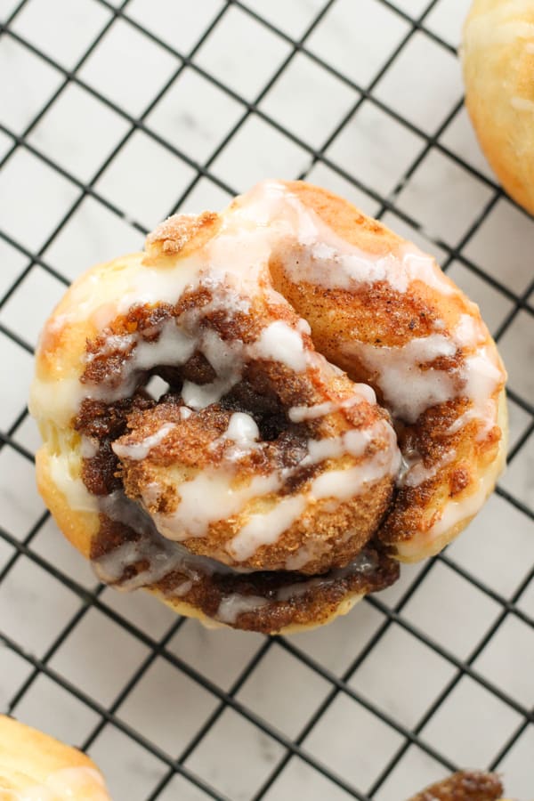 cinnamon roll on a wire rack covered with glaze.