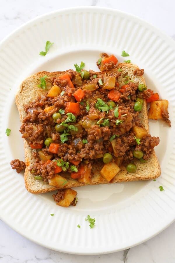 Savoury mince on top of a piece of toast on a white plate.