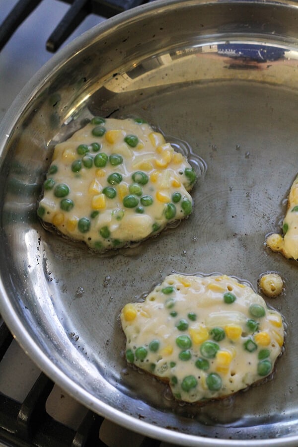 Pea & Sweet Corn Fritters cooking in a frying pan.