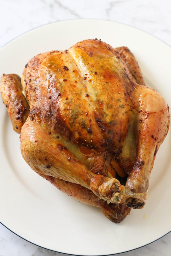 Whole roast chicken on a white plate.