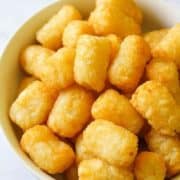 A white bowl filled with crispy tater tots.