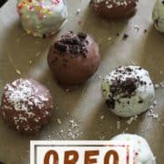oreo balls laying on baking tray covered in cookie crumbs and sprinkles.