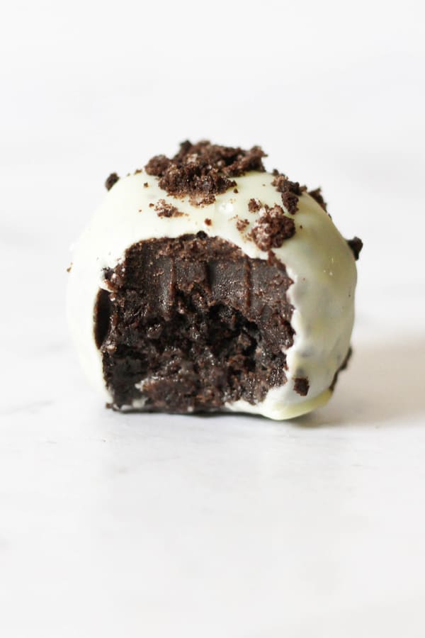oreo truffle with bite removed on a white marble background.