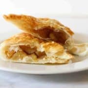 apple turnover broken into halves on a white plate.