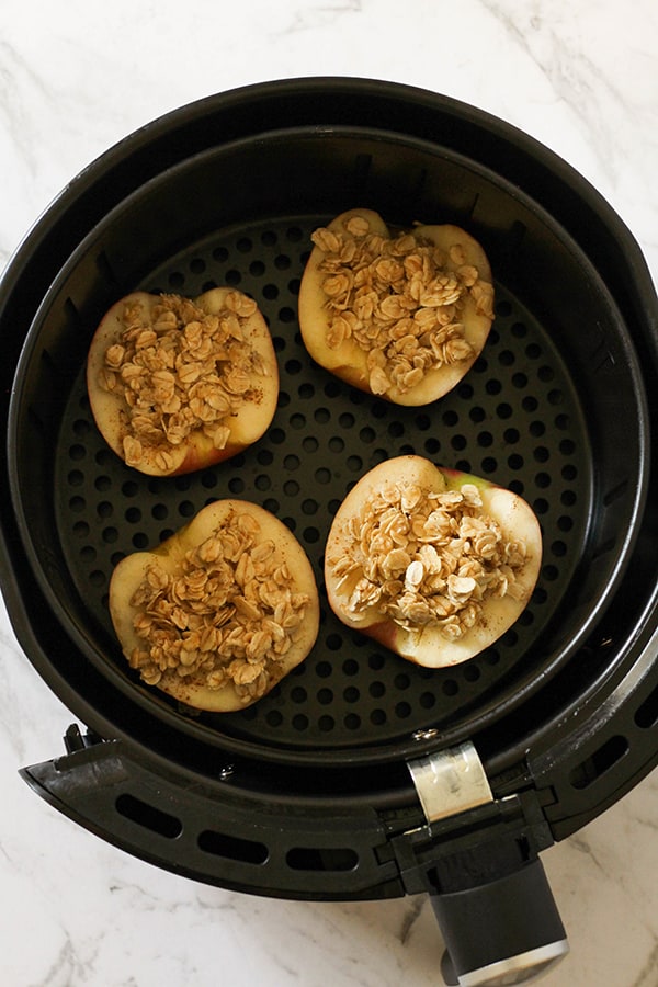 apples topped with oats in an air fryer basket.