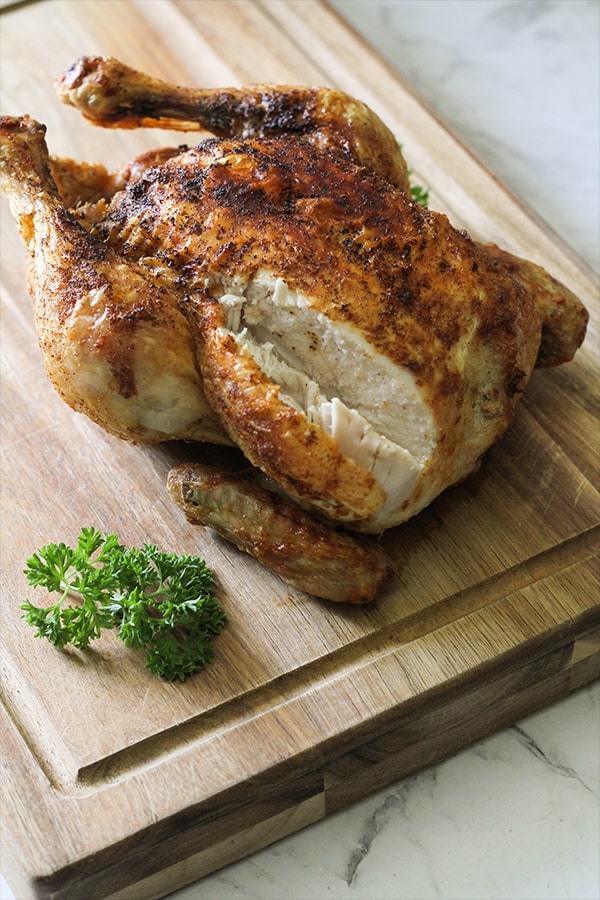 roast chicken on a wooden cutting board.