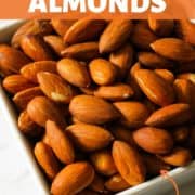Roasted almonds in a white square serving bowl.