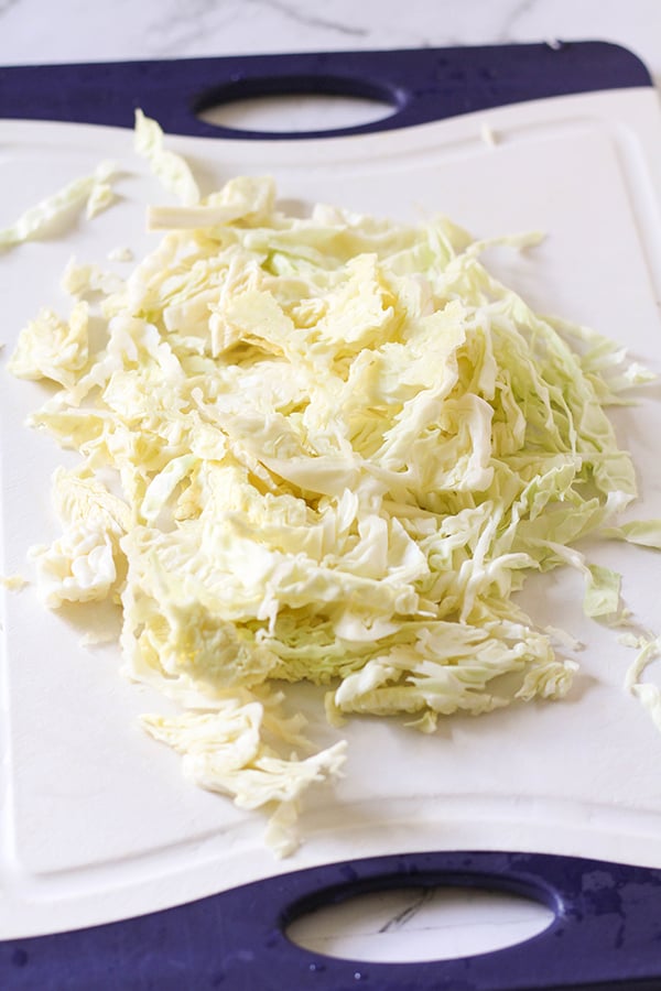 shredded cabbage on a white cutting board. 