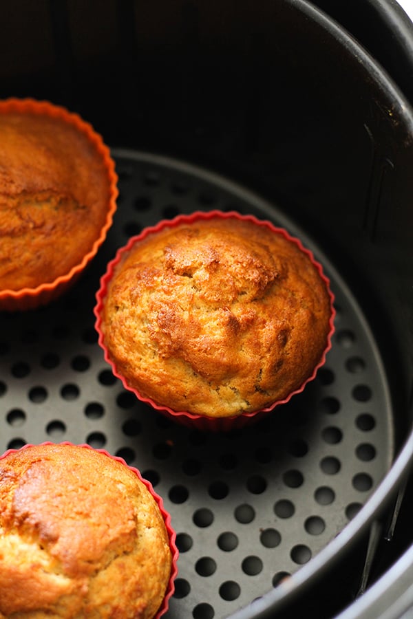 banana muffins in silicone muffin cases inside an air fryer basket.