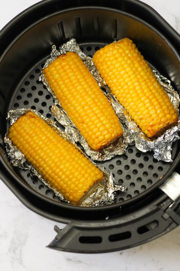corn ears in an air fryer basket.