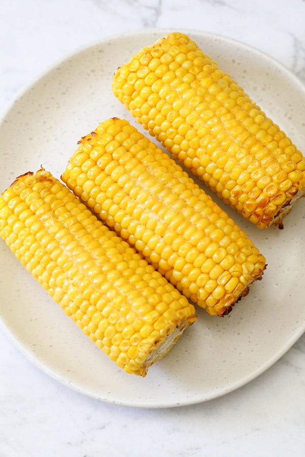 3 corn on the cob on a white plate. 