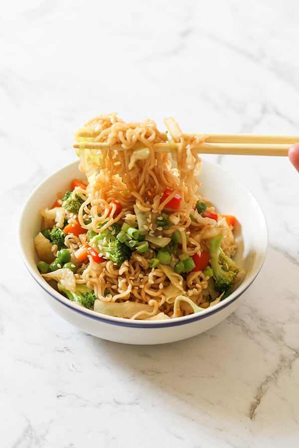 vegetable stir fry with noodles in a white bowl with chopsticks.