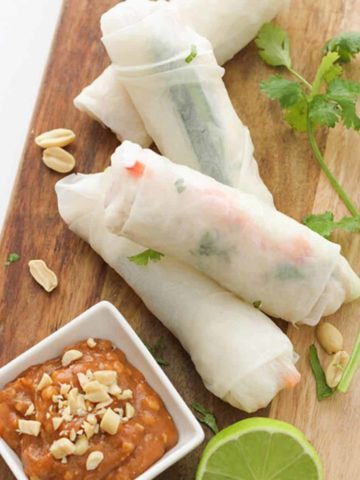 chicken rice paper rolls on a wooden serving board.
