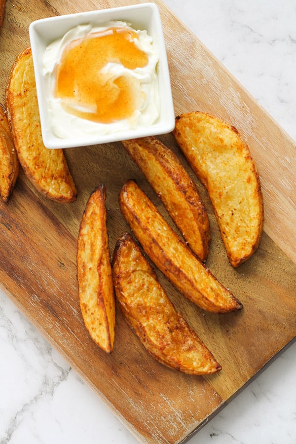 potato wedges on a wooden cutting board.