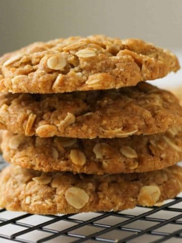 Chewy Anzac biscuits stacked on top of each other on a wire rack.