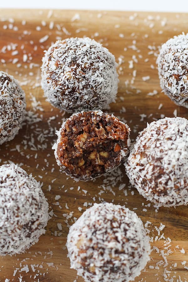 chocolate coconut energy balls on a wooden serving board.