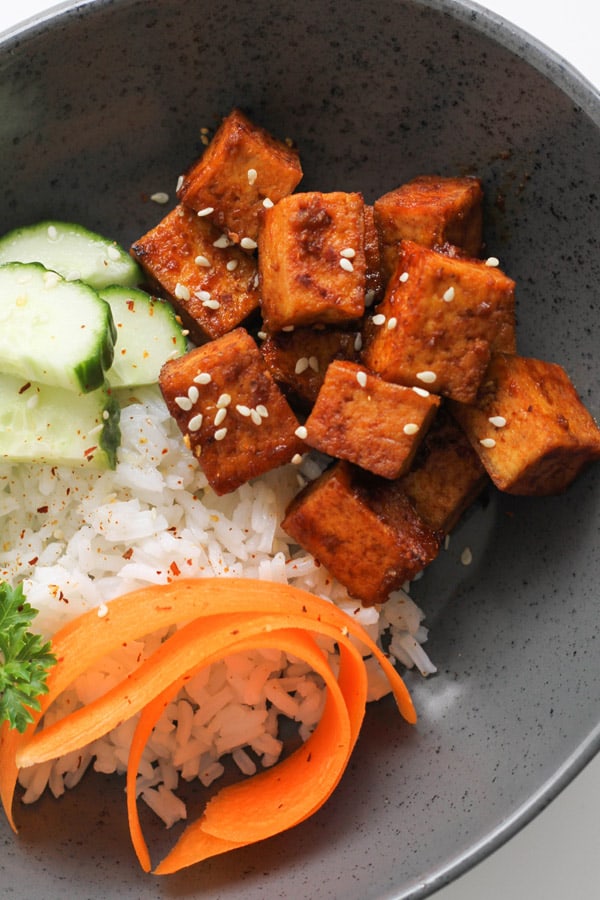 cubes of sriracha tofu on top of a bed of rice.