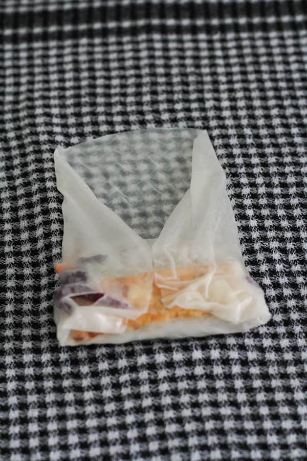a rice paper wrapper with fillings mid way through being wrapped.