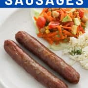 cooked sausages on a white plate with salad and rice.