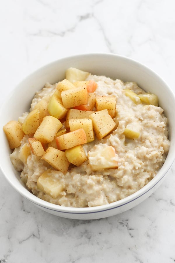 apple cinnamon oatmeal in a white bowl topped with stewed apples.